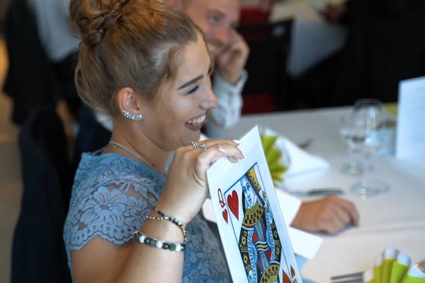 Eine Frau hält bei einer Hochzeit eine große Spielkarte fest, die Teil eines Zaubertricks mit Michele Augusta ist.